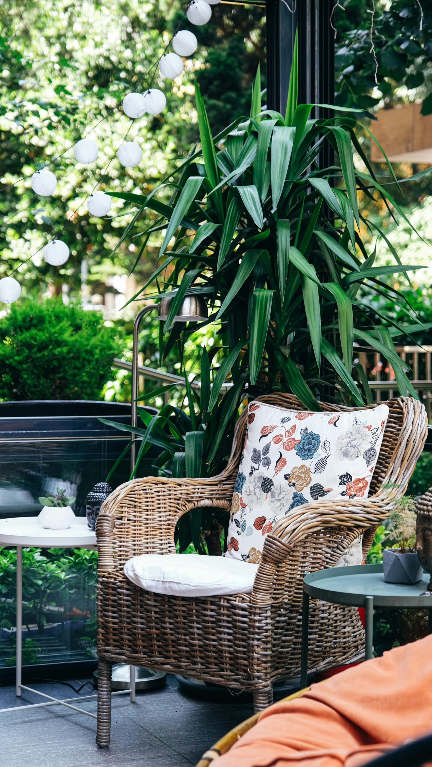 Inviting outdoor patio scene with wicker furniture, lush plants, and soft lighting.
